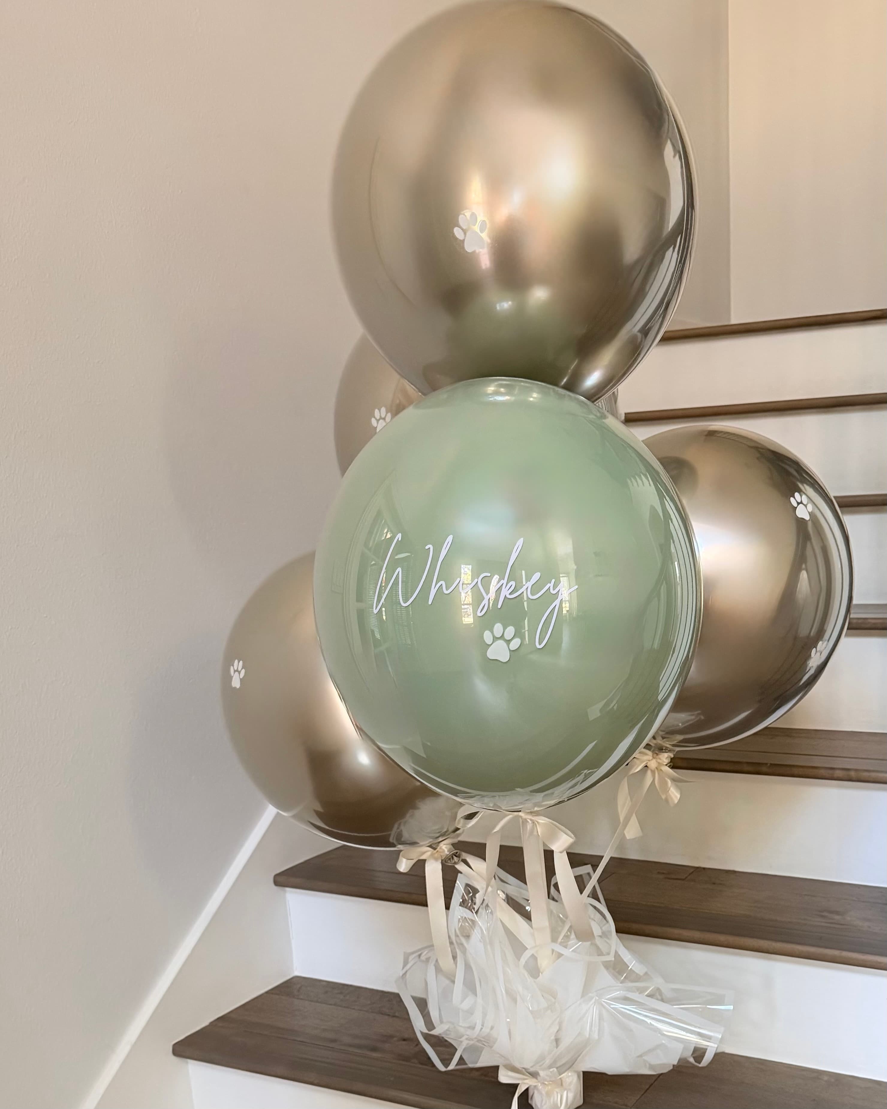 Deluxe Luxury Helium: five double-stuffed balloons with a clear overlay on a wrapped base, tied with a large statement bow